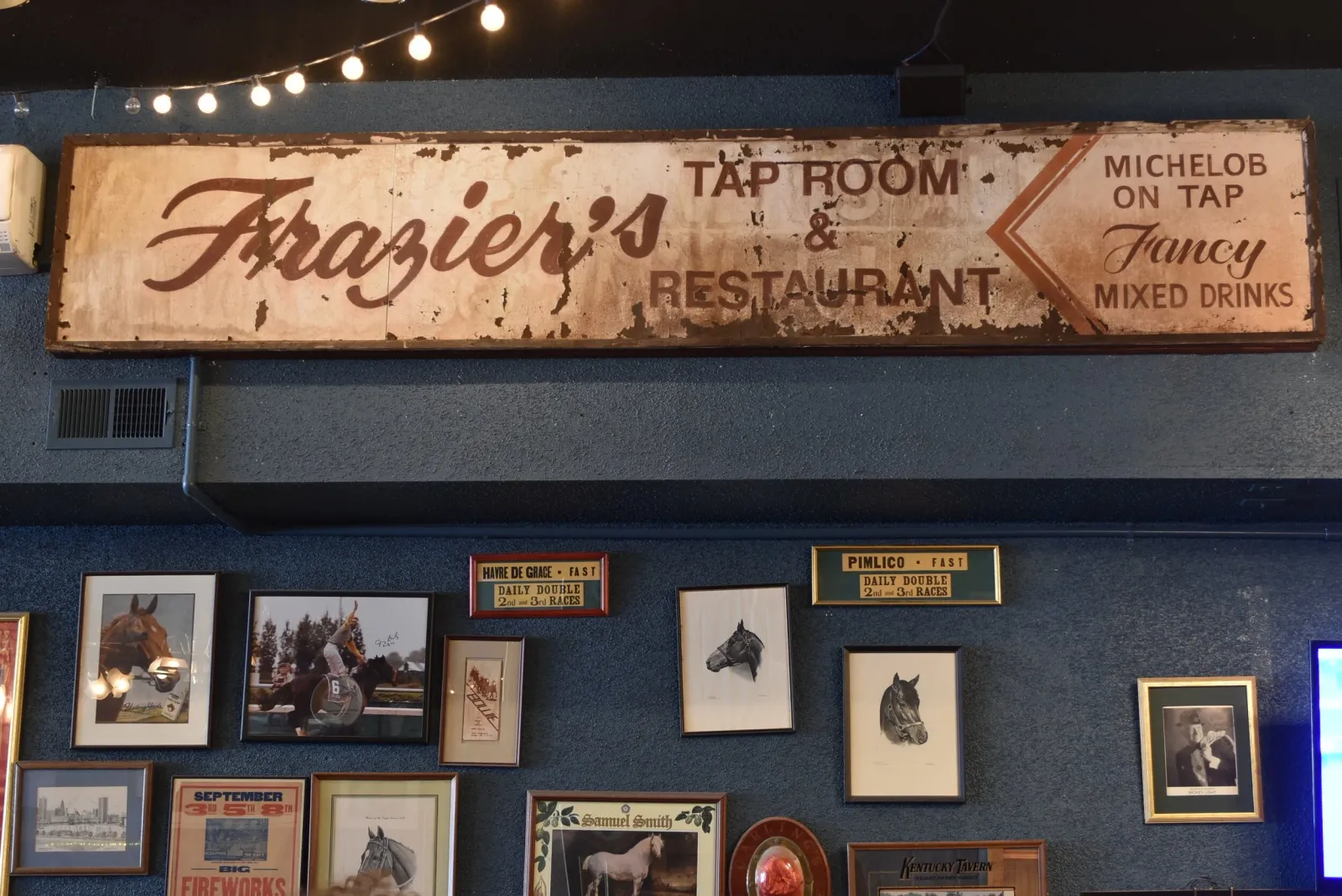 Vintage Frazier's Tap Room & Restaurant sign above framed horse racing photos inside Frazier's on the Avenue